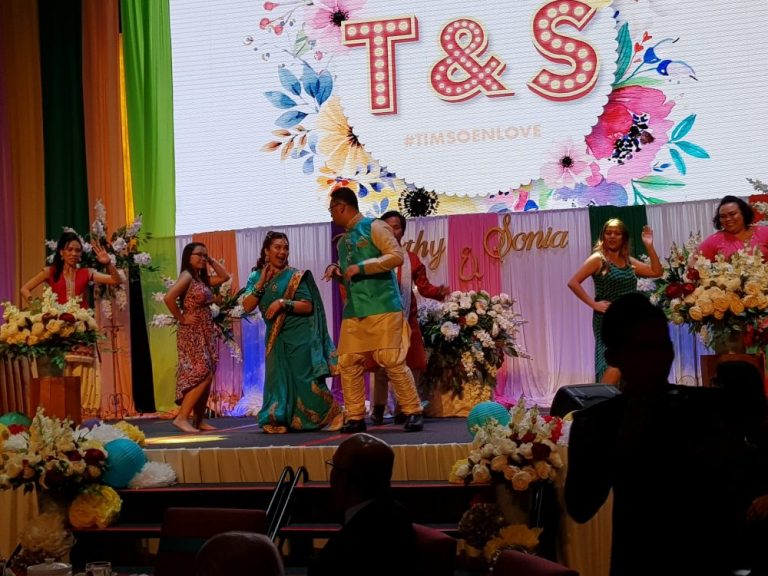 Timothy and Sonia (in green outfits) dancing on stage to Indian music