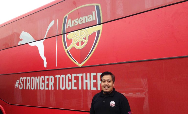 Hazreen Mubarak standing in front of an Arsenal bus.