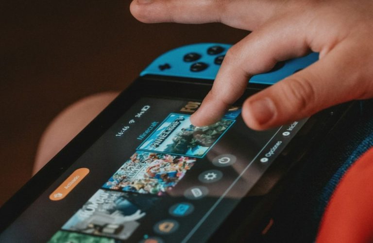A child clicks on the Minecraft game on a Nintendo Switch.