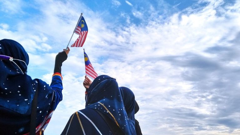 Three women in Besut, Terengganu holding the Jalur Gemilang.