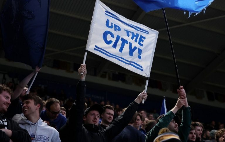 A Leicester City fan holding a banner while at the stands.