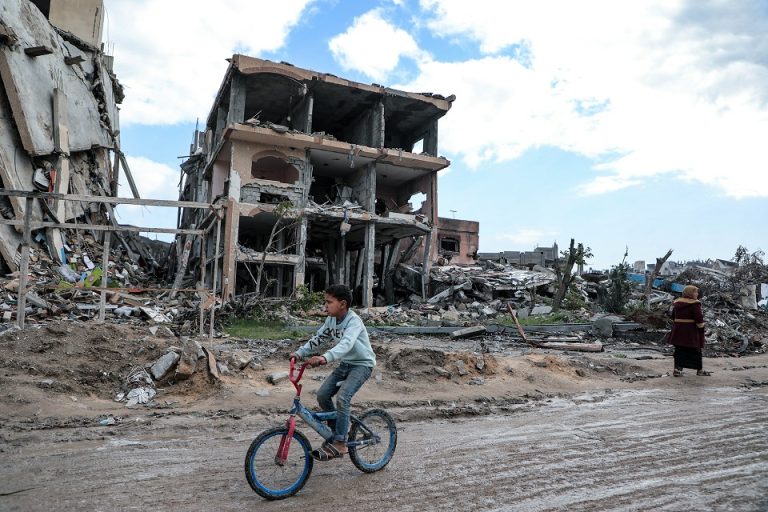 Amid the massive destruction in Jabaliya camp in Gaza, a child rides his bicycle through the camp's streets.