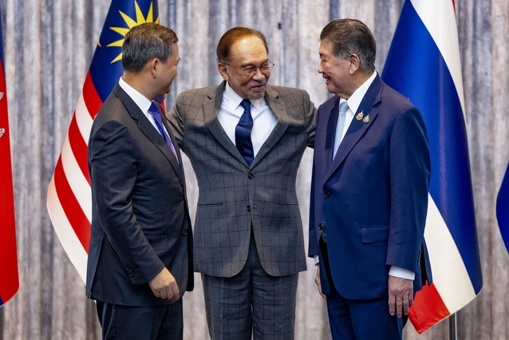 Malaysian PM Anwar Ibrahim puts his hands around Cambodian Prime Minister Hun Manet (left) and Thailand’s acting Prime Minister Phumtham Wechayachai during a special meeting regarding the Cambodia-Thailand conflict in Putrajaya on July 28, 2025.