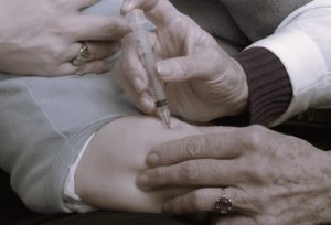 A doctor injects a baby's thigh with vaccine.