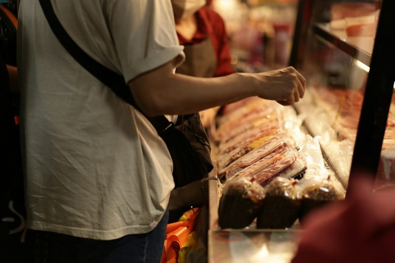 A man buying packed meat in a market.