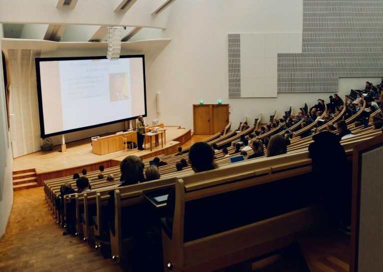 A university professor speaking to students in a lecture hall.