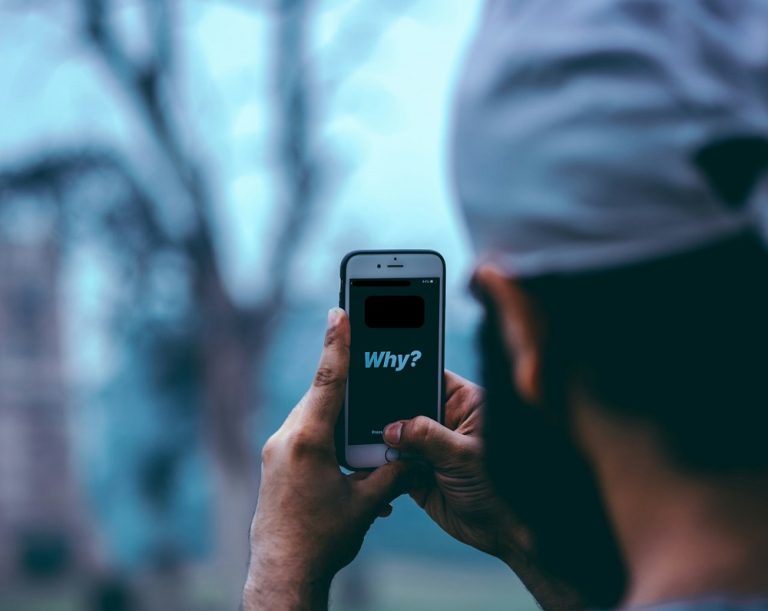 Man on a phone with the word "why' on its screen.