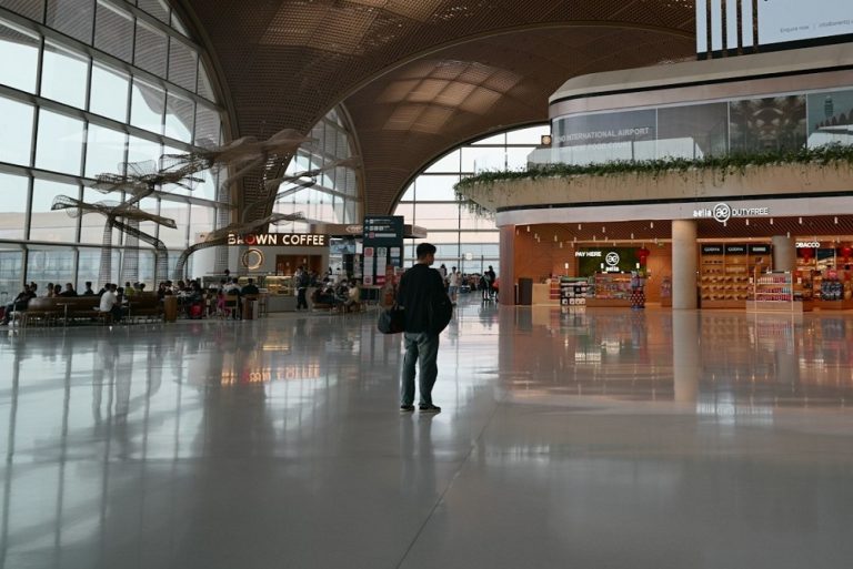 A traveller standing alone in front of a duty-free outlet in an airport in 2026.