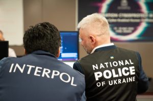 A police personnel from Ukraine and an Interpol officer sitting in front of a laptop.