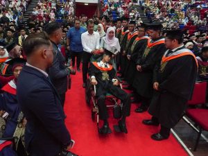 Muhammad Afiq and his parents receive warm support from fellow graduates as they accompany him on stage.
